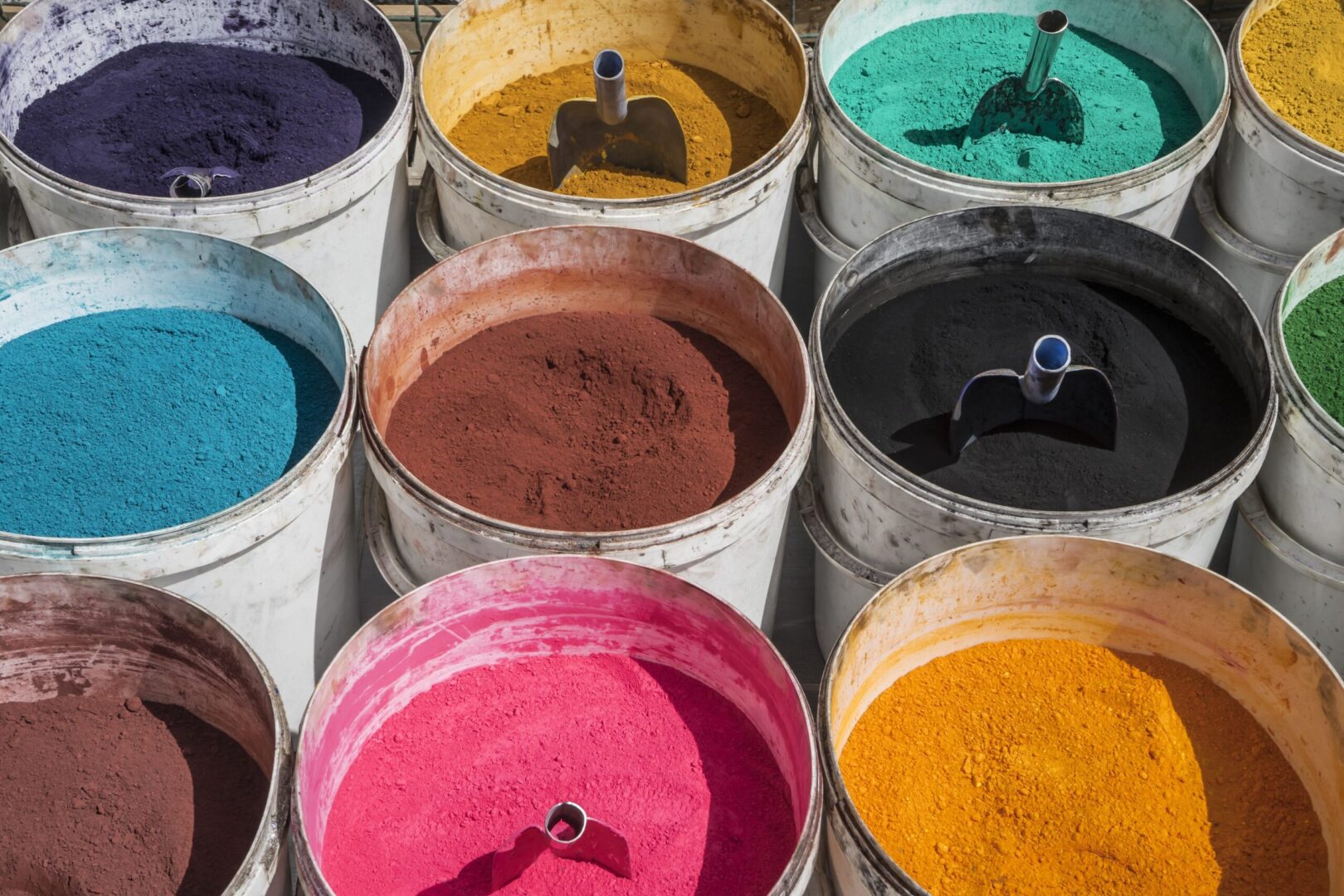 A group of buckets filled with different colored powders.