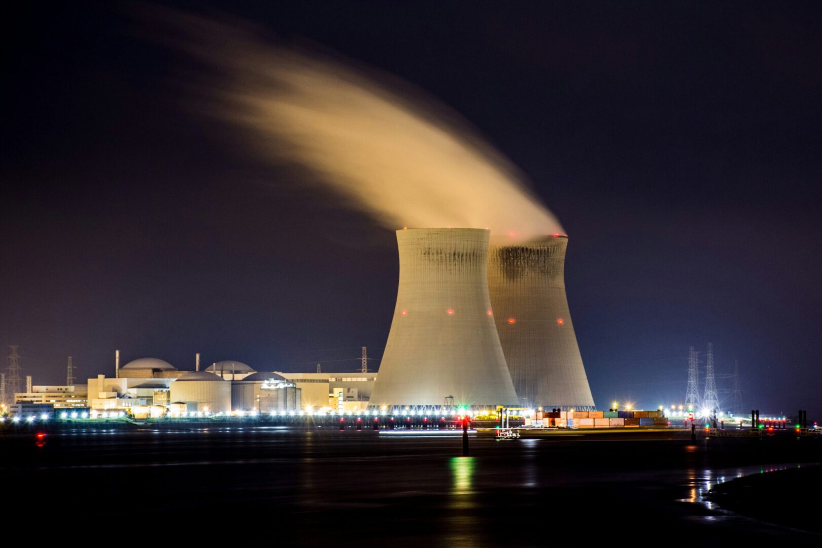 A nuclear power plant at night with smoke coming out of it.