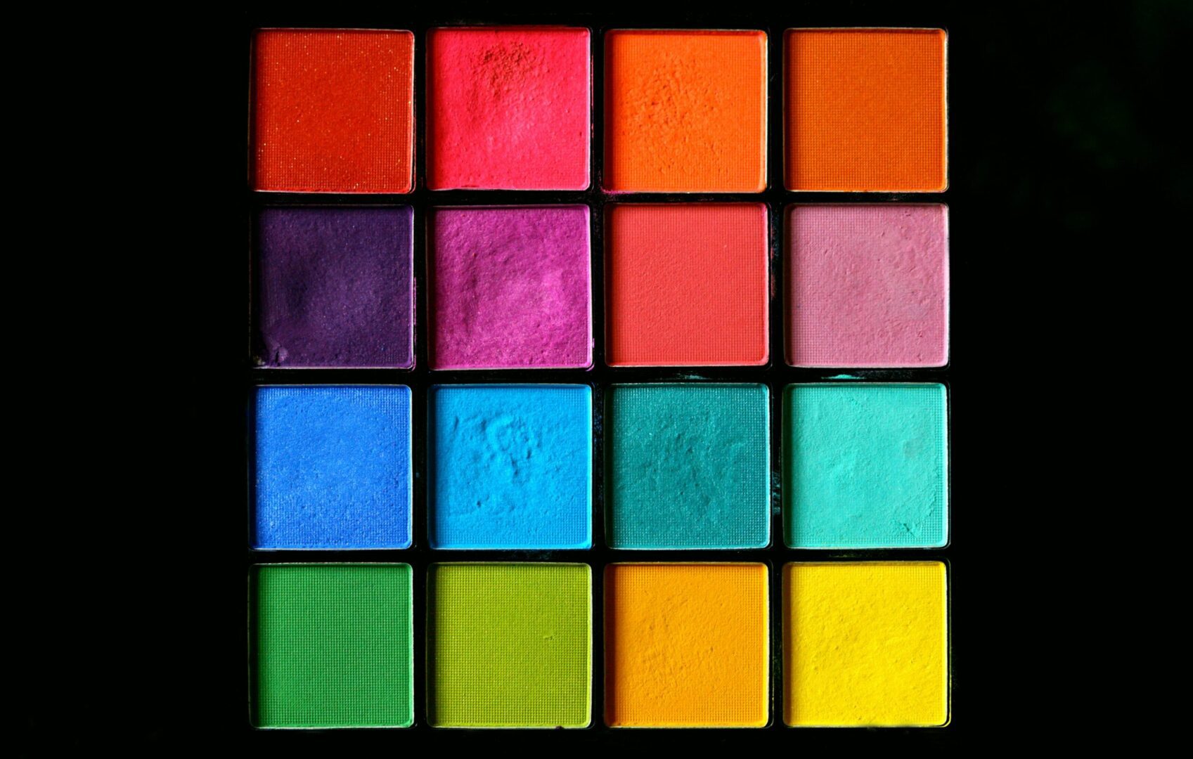 Colorful makeup palettes on a black background.