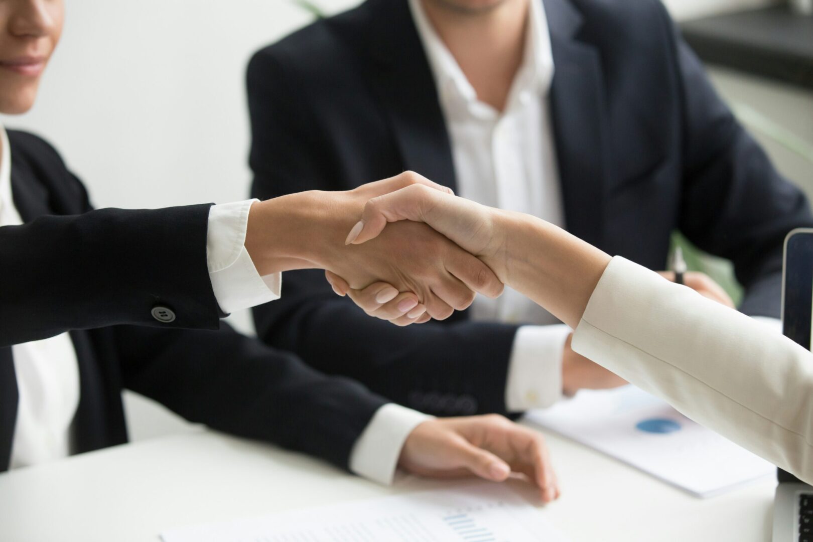 Two business people shaking hands at a meeting.