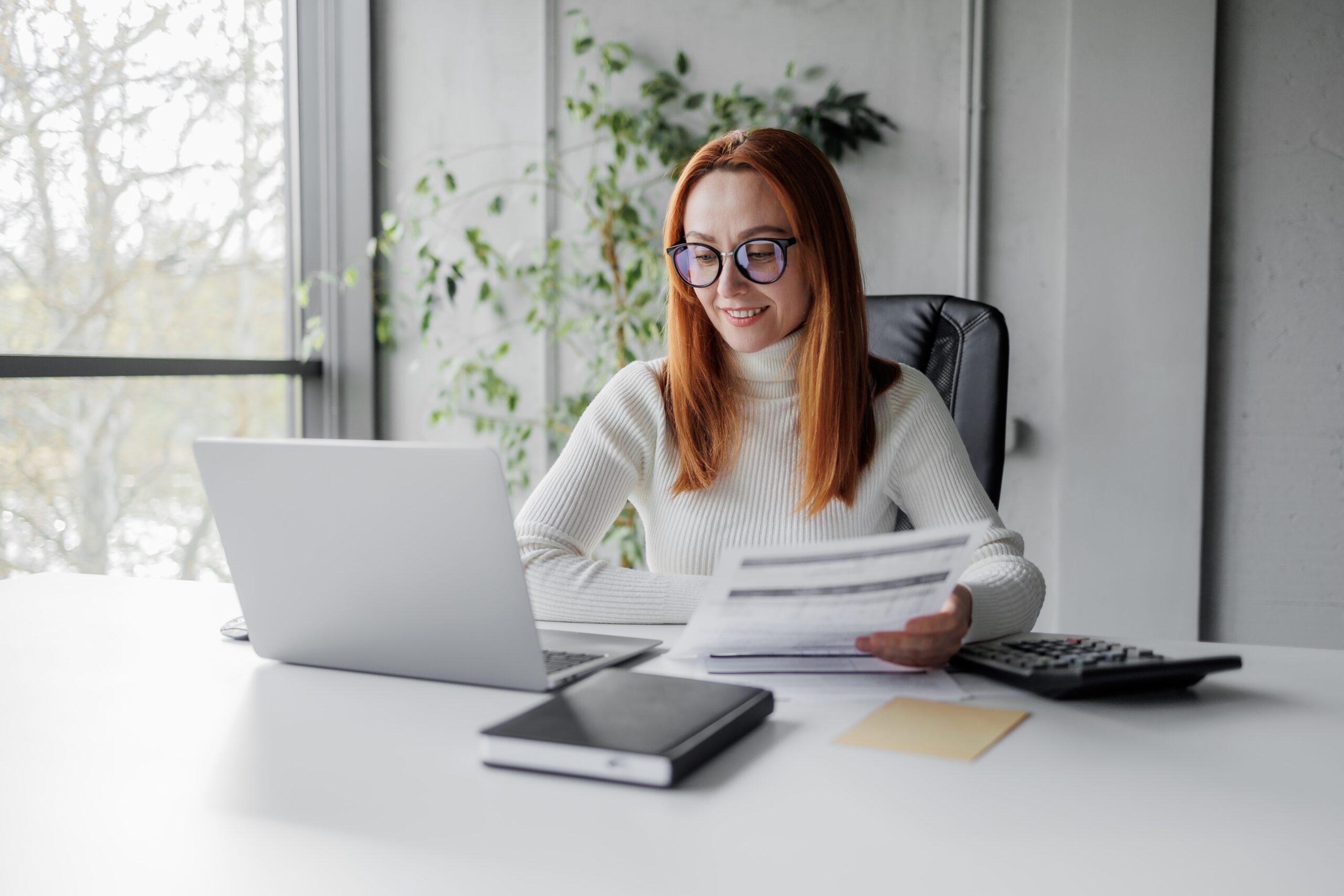 corporate business woman working in front of her laptop looking at the screen and sales reports.