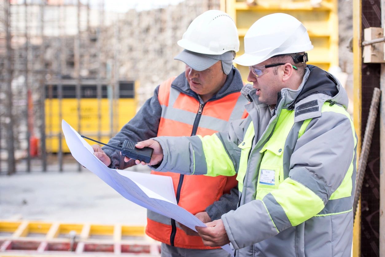 two male engineer looking at plans at a job site