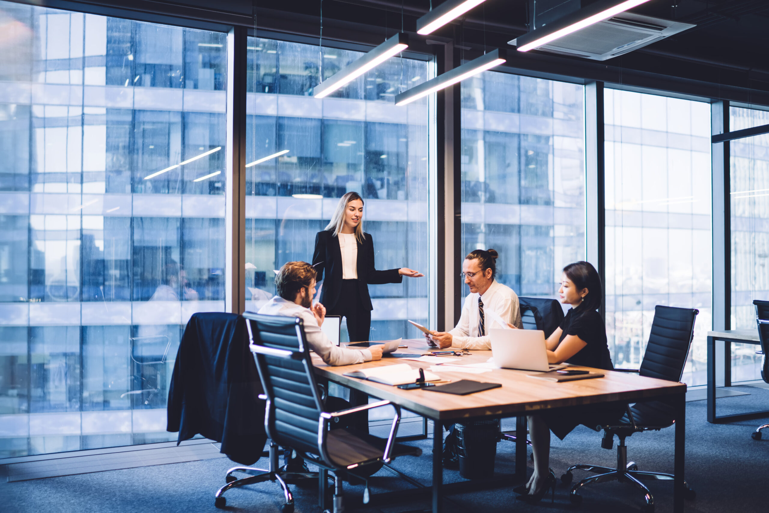 a corporate woman leads a team meeting in a conference room