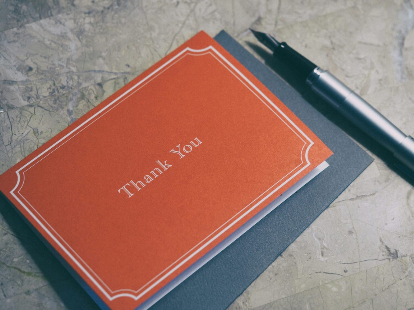 bright red thank you card with a vintage ink pen beside it