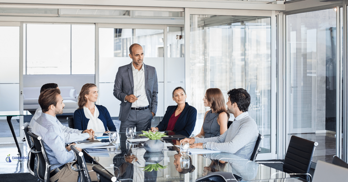 A group of corporate workers surrounding a conference table in a meeting room