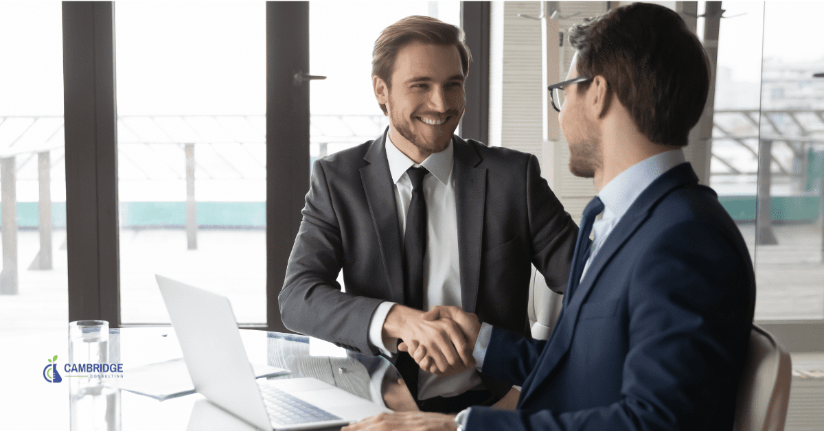 two corporate men shaking hands in a conference room