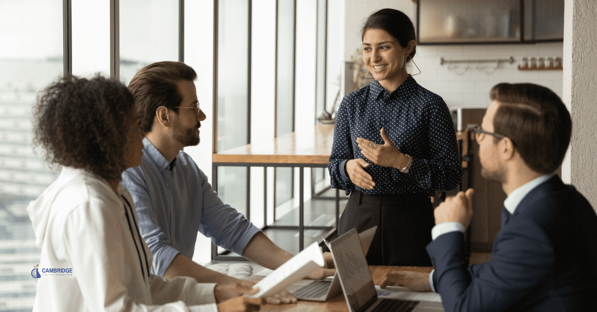 men and woman in a corporate meeting surrounding a table in an office