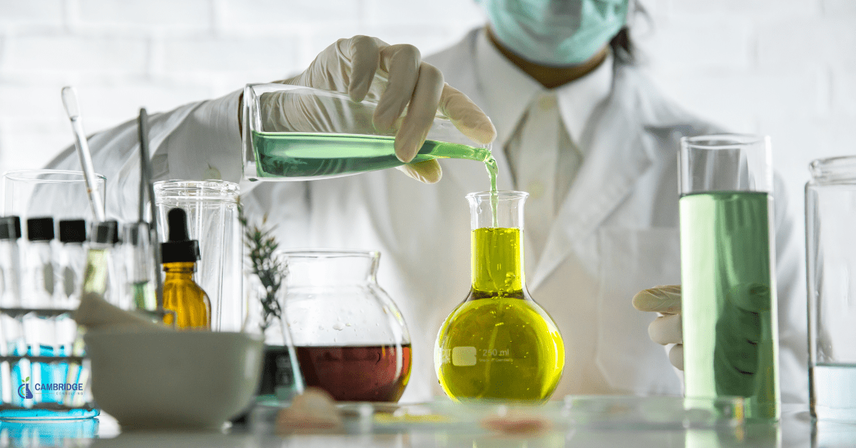 scientist in a mask working with multicolored liquids in various glass beakers