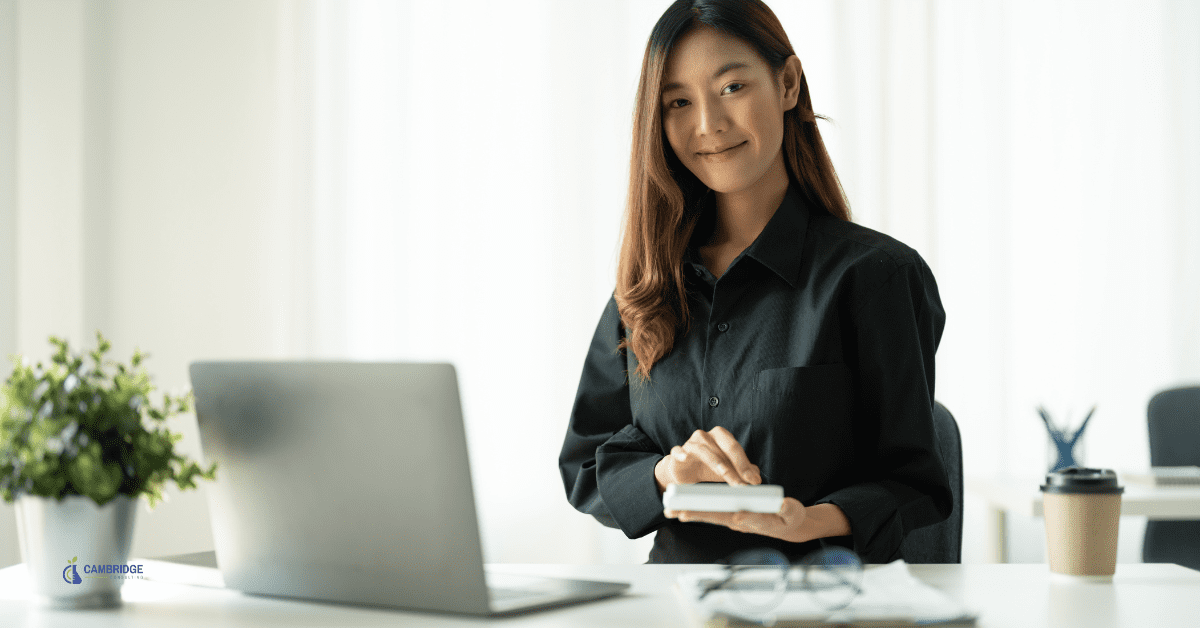 A young business woman working at her desk in a well-lit office.