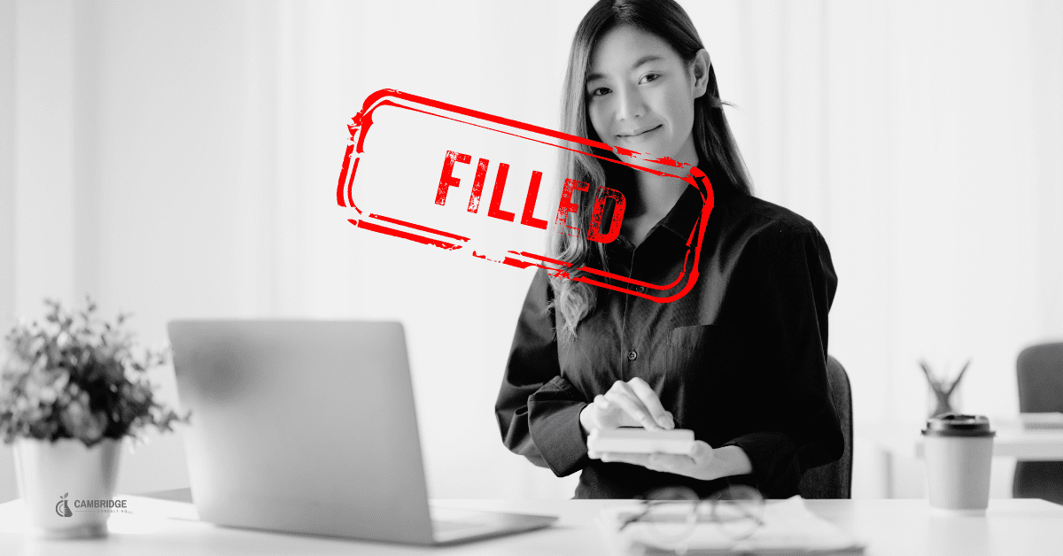 Black and white image off a corporate woman sitting in her office with a red stamp overlay saying "filled" in reference to the job listing.