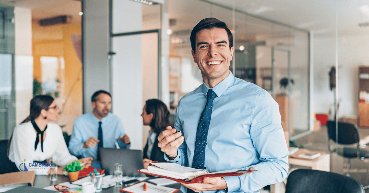 corporate man smiling in front of his work colleagues