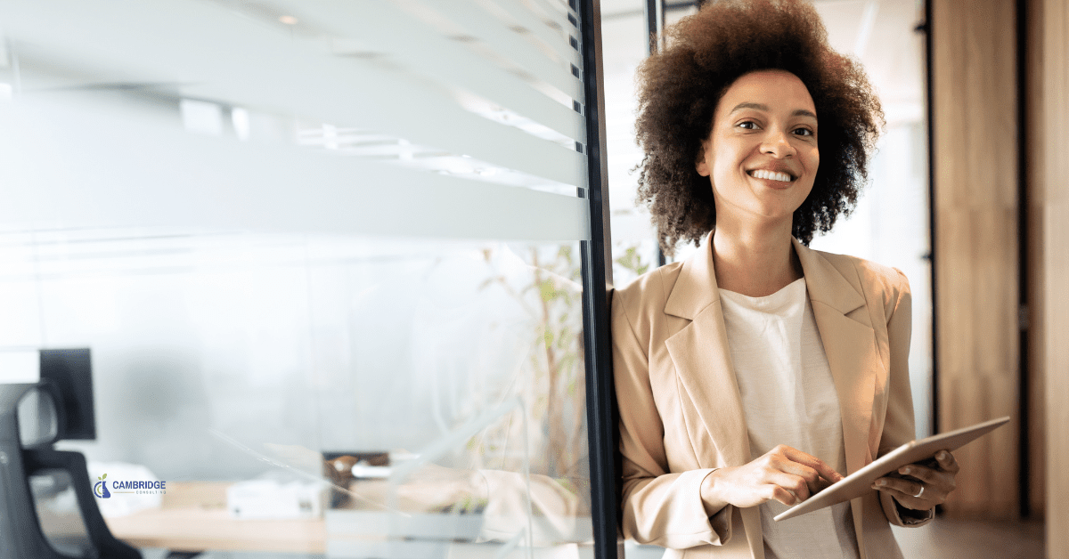 Black woman standing in an office doorway smiling holding a clipboard