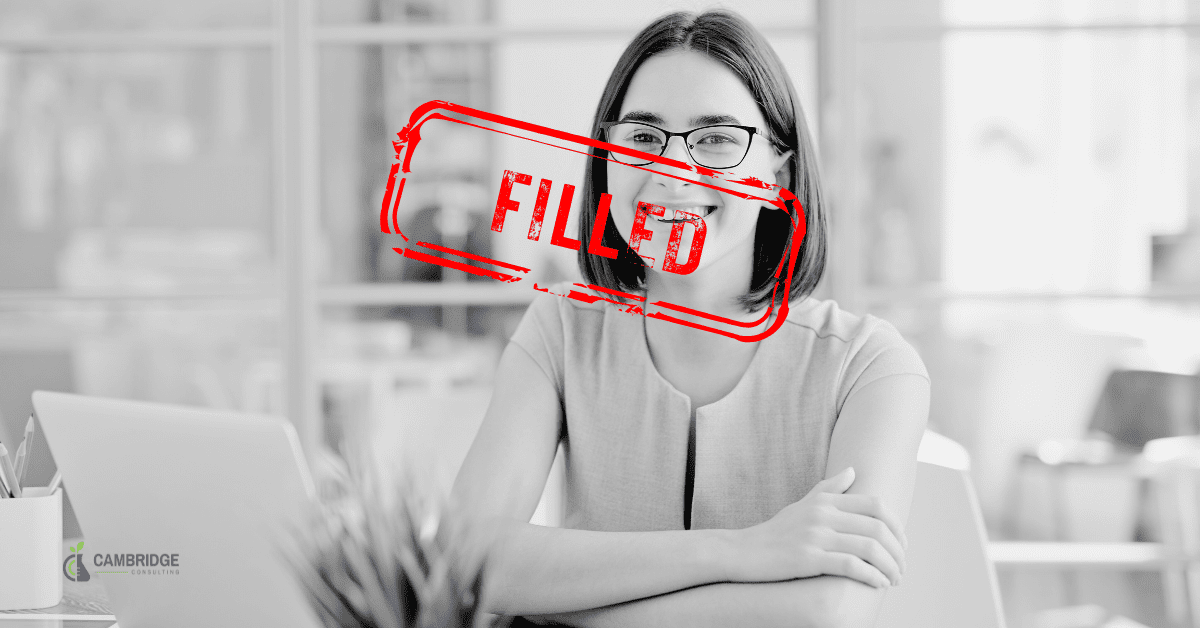 black and white image of a woman smiling at her desk with red stamp overlay of text that says "filled"