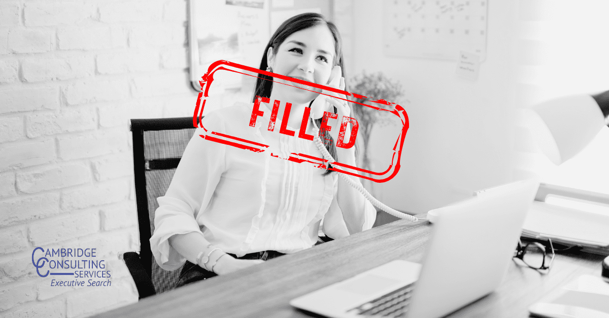 a black and white image of a woman smiling as she talks on the phone in her corporate office with a red stamp overlay that says "filled," and the Cambridge Consulting Services logo in the bottom right corner