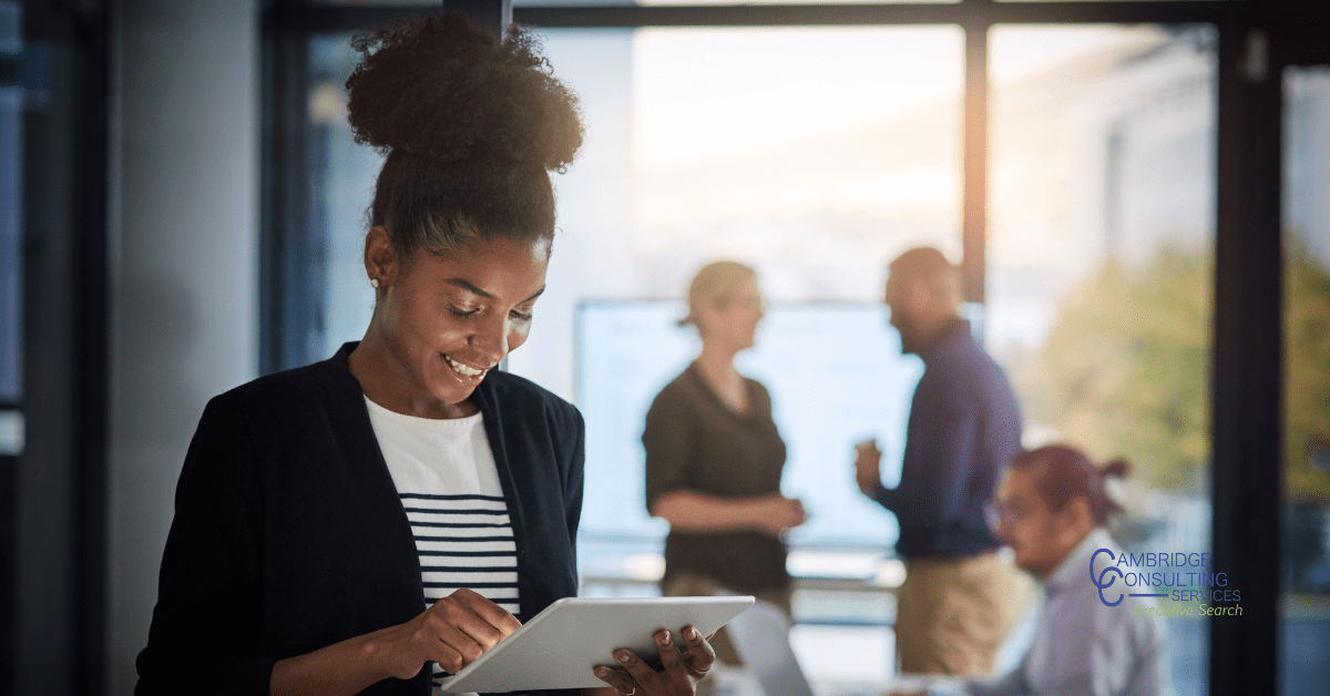 a photo of a woman and her colleagues at work with the Cambridge consulting services logo in the bottom right hand corner
