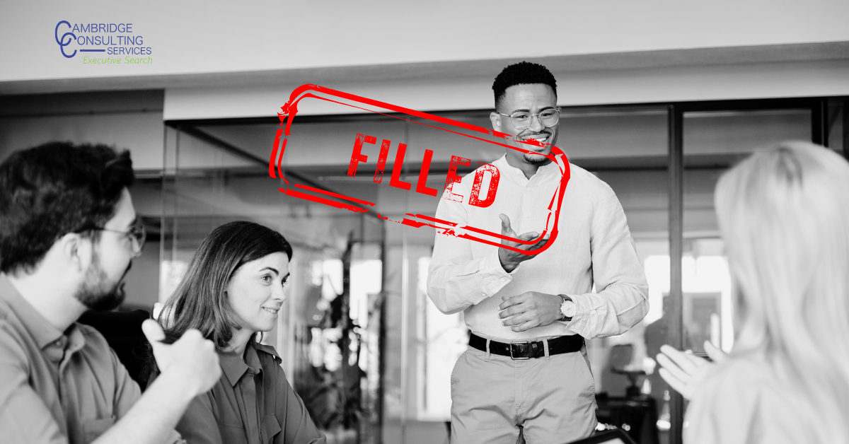 a man speaking to his team at a conference table with a red text overlay that says "filled" in capital letters, witht he Cambridge Consulting Services logo in the top left corner